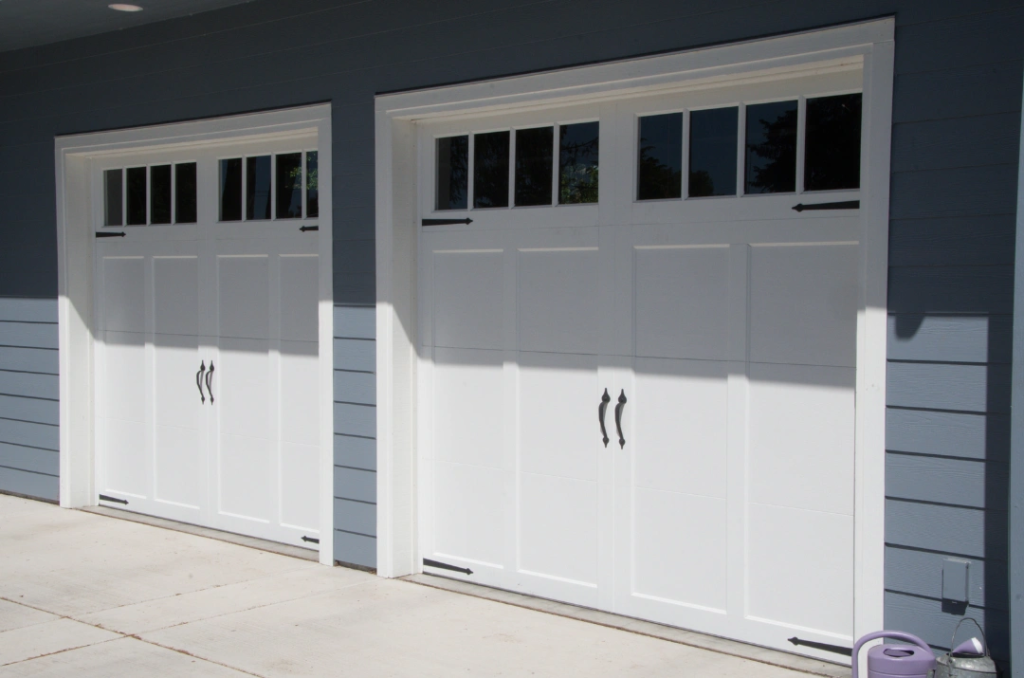 Modern garage with two white garage doors featuring window panels, offering a sleek and clean look.